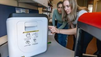 Two students operate a 3D printer